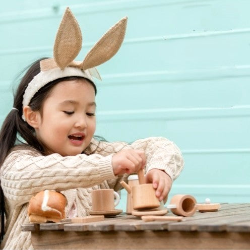 Child creating a fun craft activity using colourful paper and glue, with wooden toys scattered on the table for imaginative play.