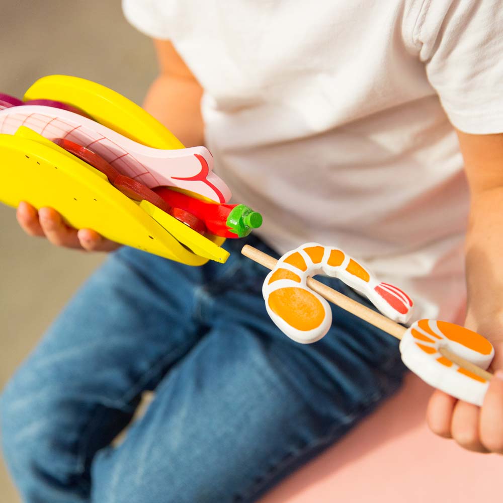 Make Me Iconic 21-piece wooden toy play Taco Kit featuring stand-up taco shells, prawns on skewers, paper takeaway bags, felt toppings, and pretend condiments like chilli sauce and sour cream for imaginative role play.