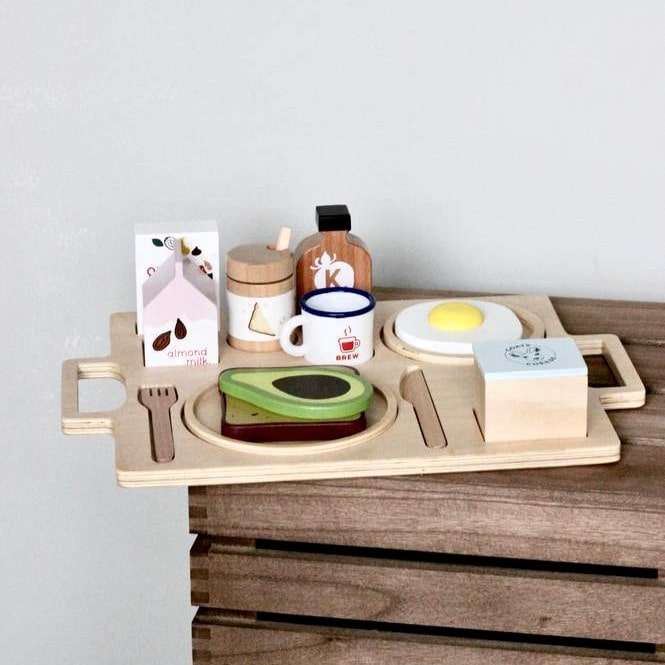 21-piece wooden toy breakfast tray featuring avocado on toast, goats cheese, tahini, kombucha, and other café-style foods for pretend play fun.
