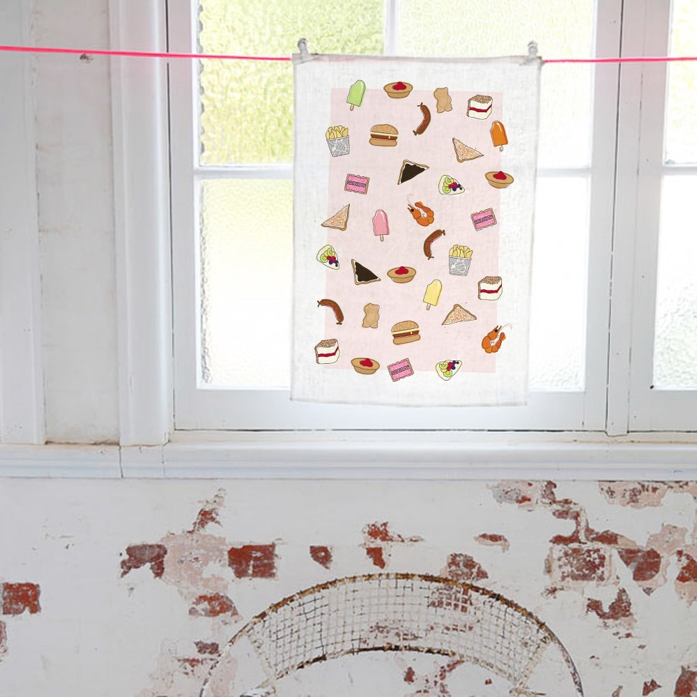 Make Me Iconic tea towel featuring iconic Australian foods, such as Vegemite toast, fairy bread, meat pies, pavlova, and lamingtons. A colourful, quirky kitchen accessory celebrating Aussie culture and nostalgia