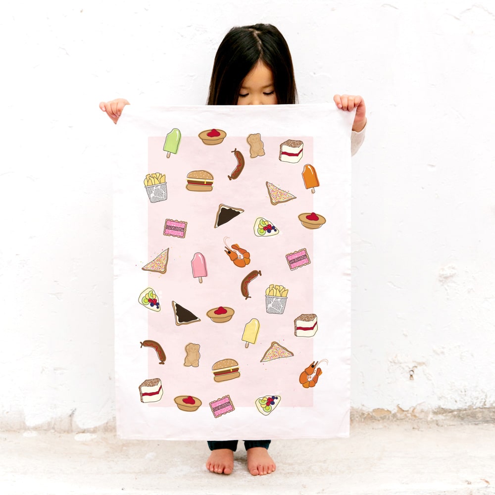 Make Me Iconic tea towel featuring iconic Australian foods, such as Vegemite toast, fairy bread, meat pies, pavlova, and lamingtons. A colourful, quirky kitchen accessory celebrating Aussie culture and nostalgia