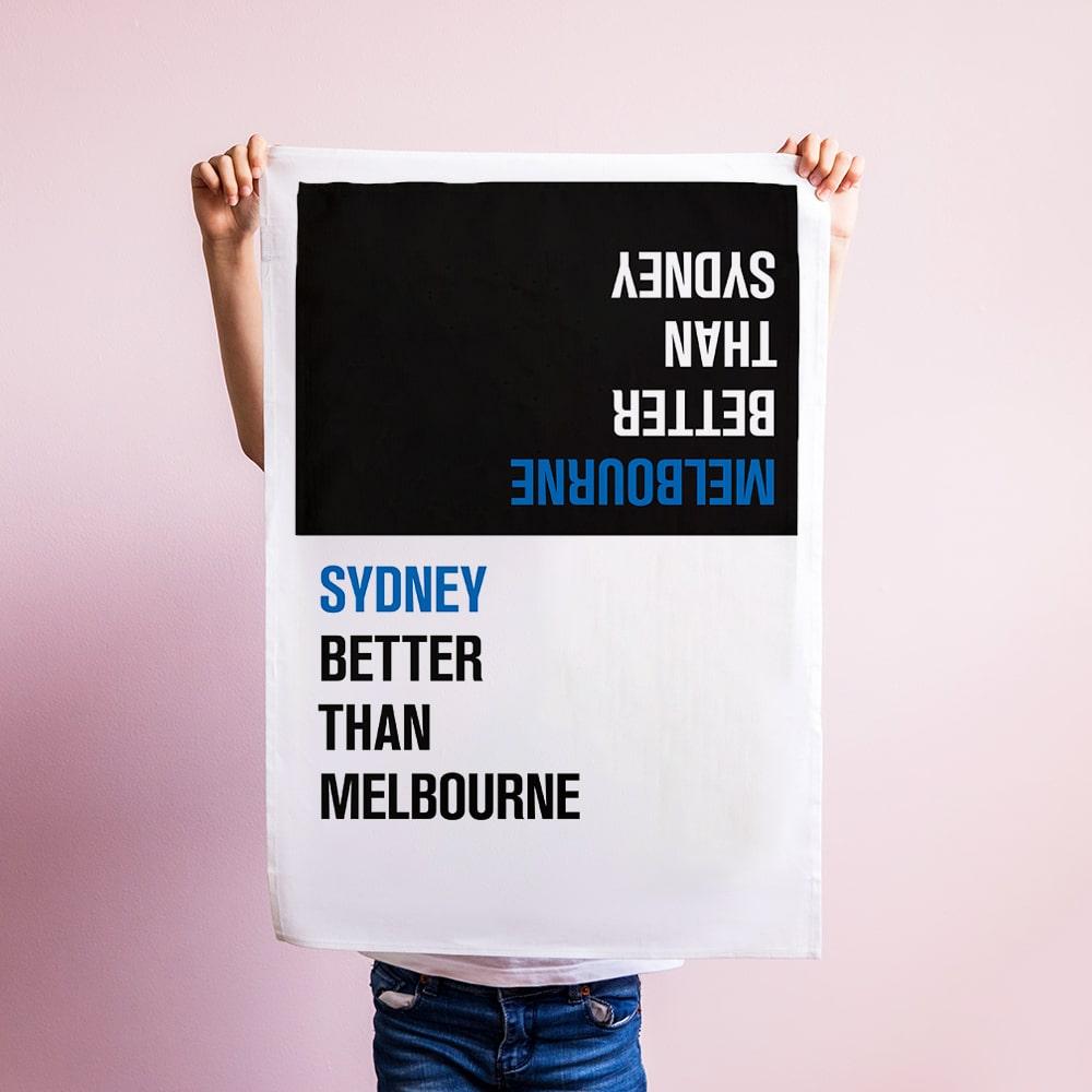 Make Me Iconic Choice Tea Towel with bold double-sided print, Melbourne vs Sydney rivalry in playful, nostalgic kitchen style.