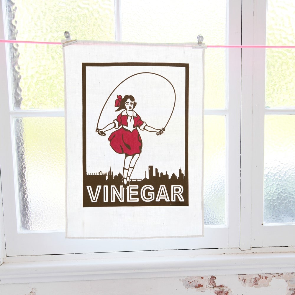 Make Me Iconic Skipping Girl tea towel featuring Melbourne’s iconic Little Audrey neon sign, a nostalgic tribute to the city’s skyline.