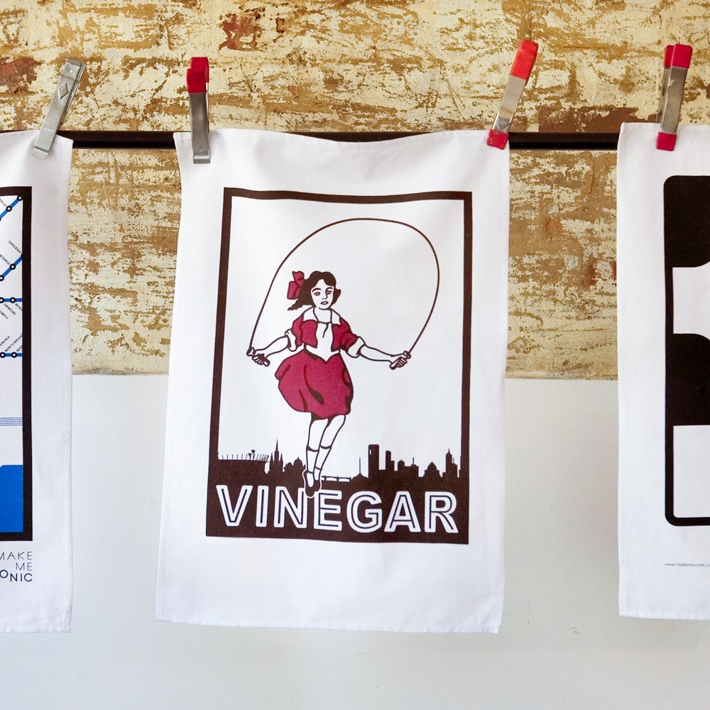 Make Me Iconic Skipping Girl tea towel featuring Melbourne’s iconic Little Audrey neon sign, a nostalgic tribute to the city’s skyline.
