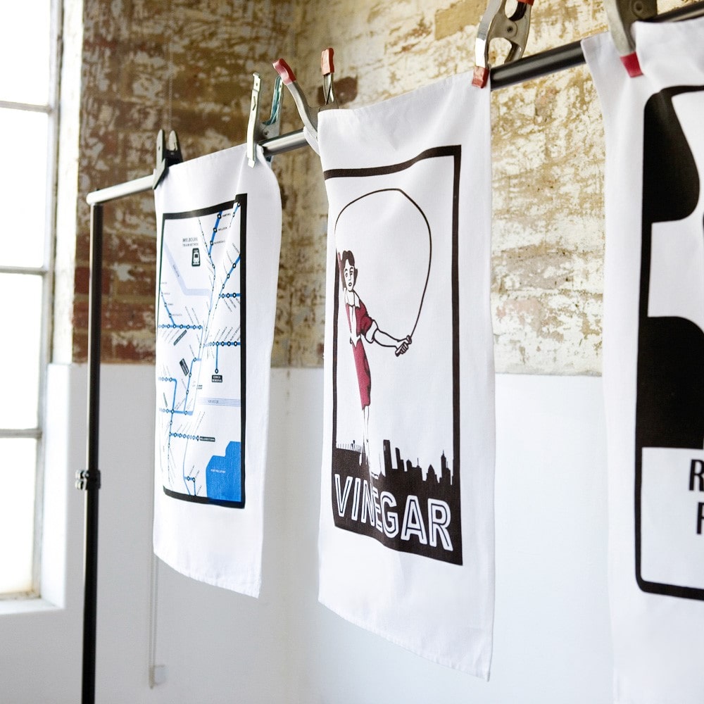 Make Me Iconic Skipping Girl tea towel featuring Melbourne’s iconic Little Audrey neon sign, a nostalgic tribute to the city’s skyline.