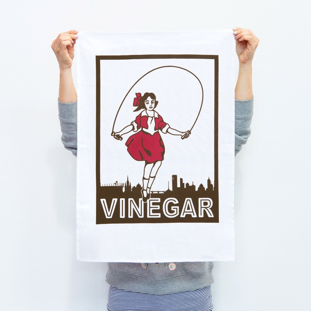 Make Me Iconic Skipping Girl tea towel featuring Melbourne’s iconic Little Audrey neon sign, a nostalgic tribute to the city’s skyline.