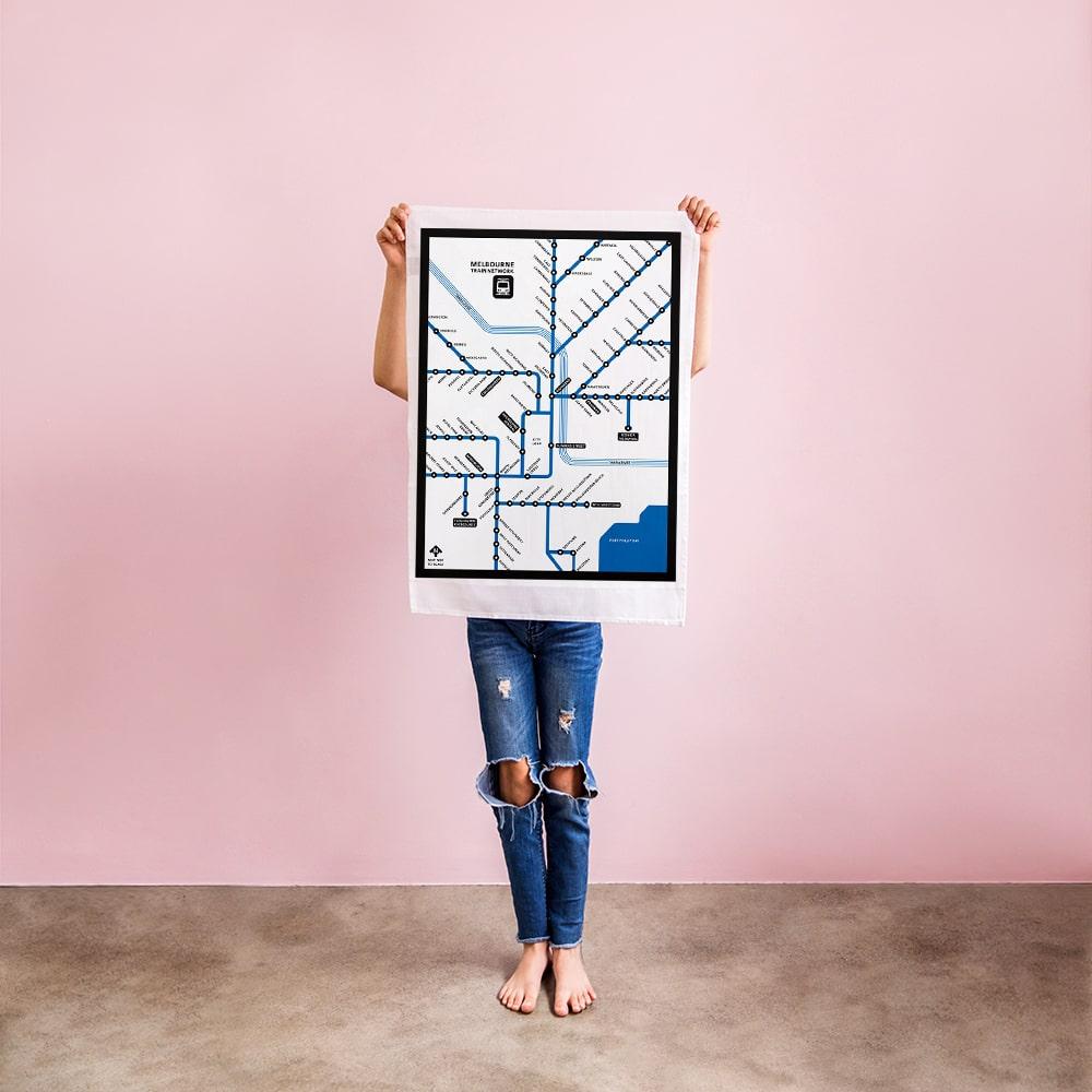 Make Me Iconic Melbourne Train Network Tea Towel featuring an illustrated map of Melbourne’s railway system, an Australian souvenir celebrating iconic public transport.