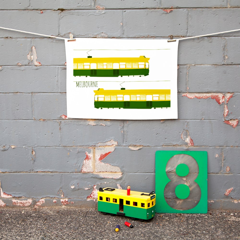 Make Me Iconic Melbourne Tram Tea Towel featuring the classic green and gold W-Class tram with vintage destination banner, an iconic Australian gift and kitchen textile.