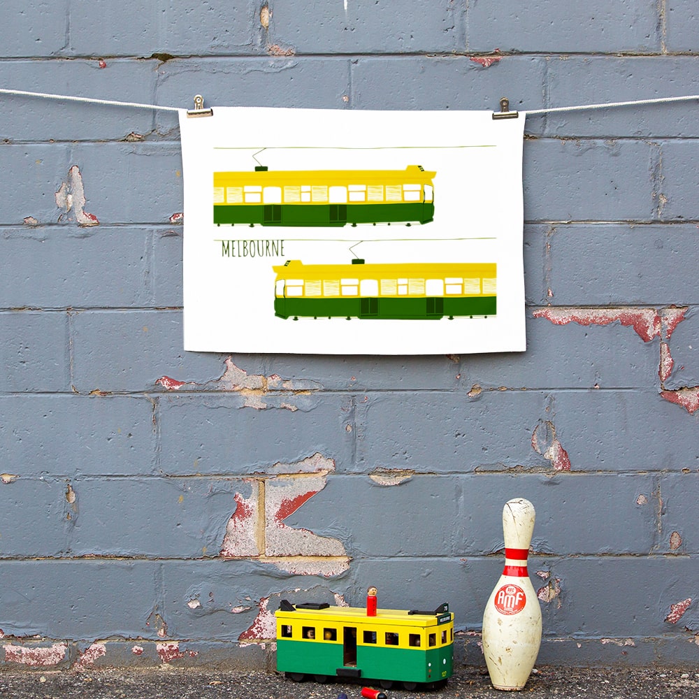 Make Me Iconic Melbourne Tram Tea Towel featuring the classic green and gold W-Class tram with vintage destination banner, an iconic Australian gift and kitchen textile.
