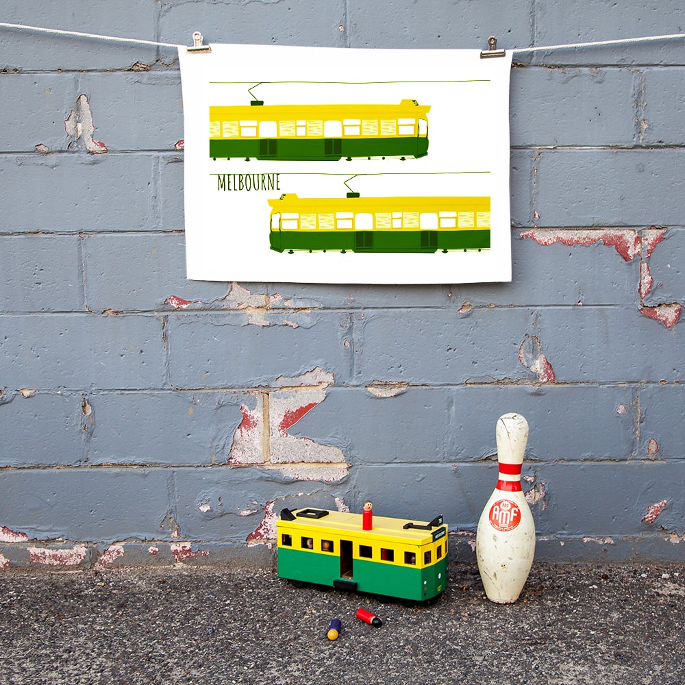 Make Me Iconic Melbourne Tram Tea Towel featuring the classic green and gold W-Class tram with vintage destination banner, an iconic Australian gift and kitchen textile.