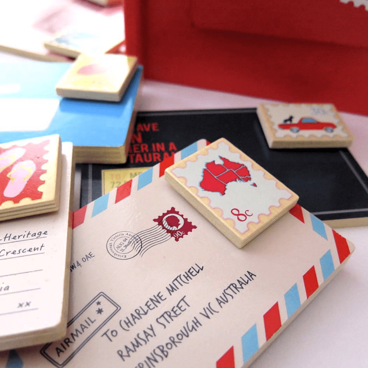 Wooden Australian post box toy with working mail slot, 6 wooden letters, and 6 Velcro stamps perfect for imaginative pretend play and storytelling.