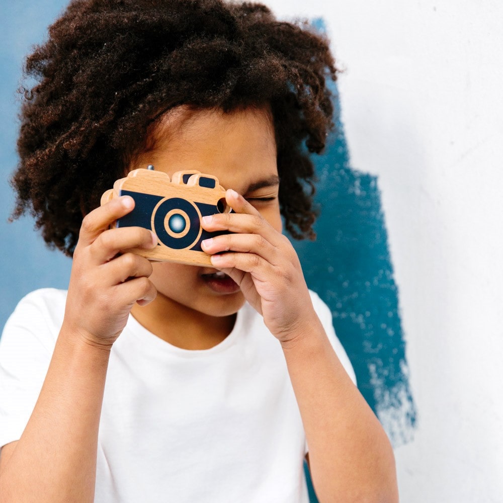 Wooden toy camera for kids with real viewfinder and pressable button, designed for imaginative pretend play and creative role-play photography fun.