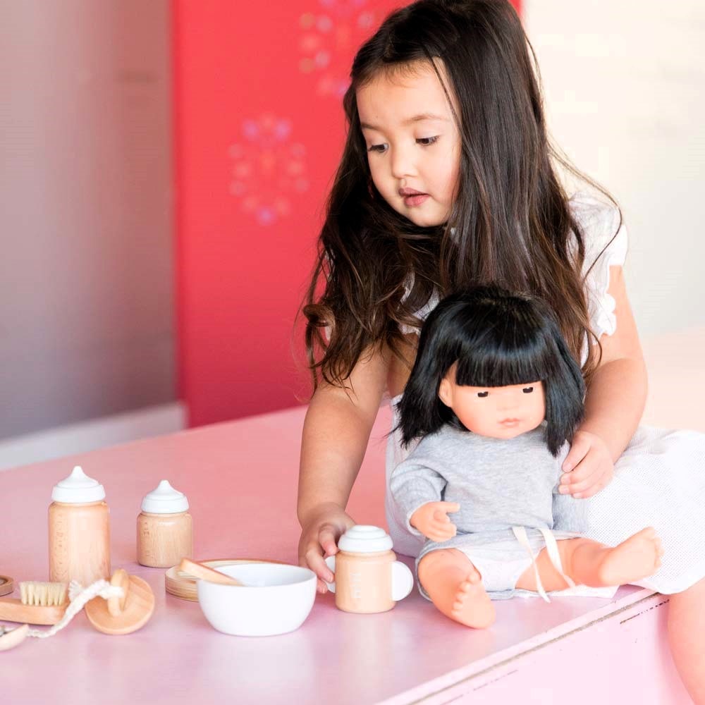 Make Me Iconic 11-piece wooden doll accessory kit with bottles, sippy cup, bowl, fork, spoon, brush with real bristles, comb, teether, and clip-on pacifier – perfect for pretend play.