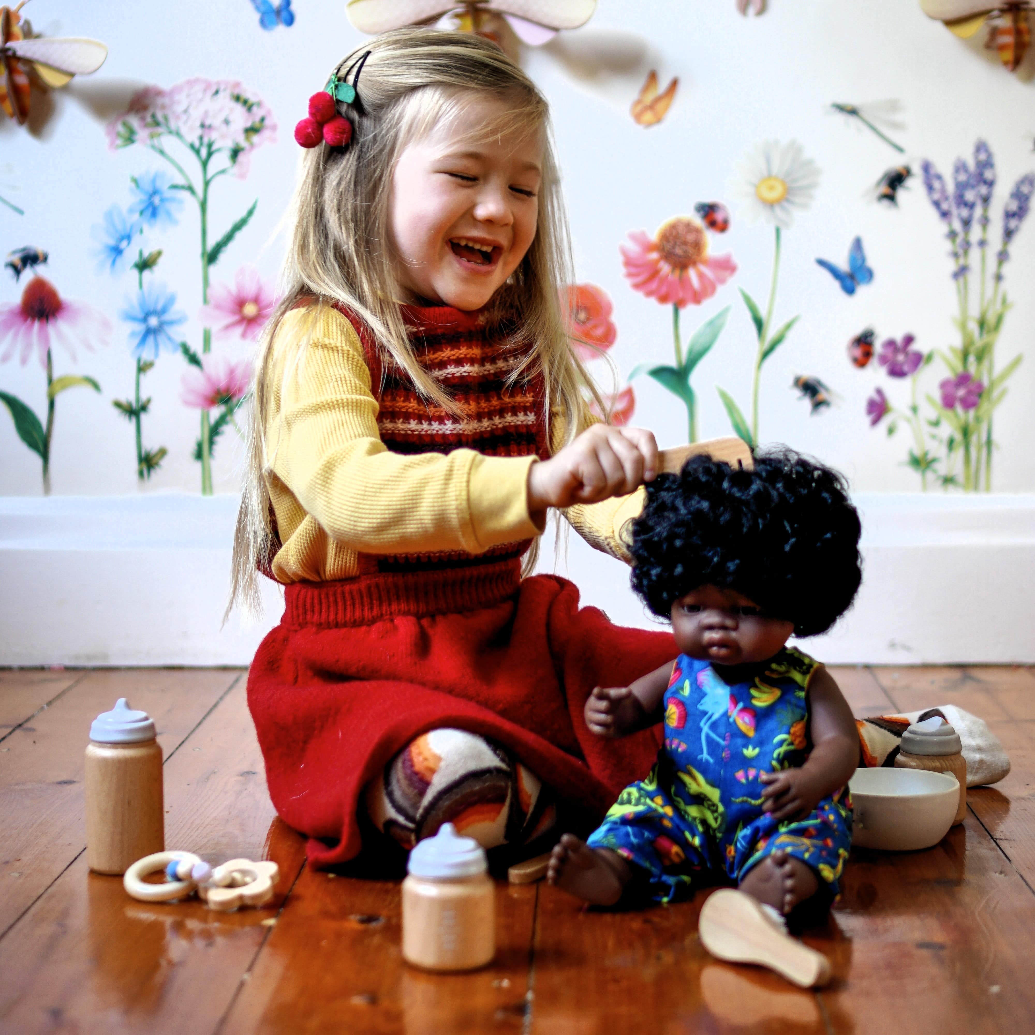 Make Me Iconic 11-piece wooden doll accessory kit with bottles, sippy cup, bowl, fork, spoon, brush with real bristles, comb, teether, and clip-on pacifier – perfect for pretend play.