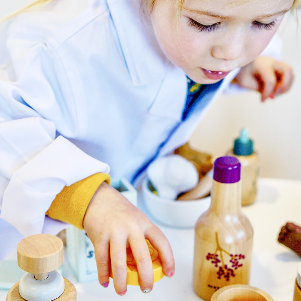 Wooden toy Natural Healers Kit with pestle and mortar, pretend Epsom salts, Manuka honey, bone broth, Tea Tree oil dropper, Boo Boo lotion, vitamins, arnica cream, herbal tea bags, and felt herbs for imaginative wellness play.