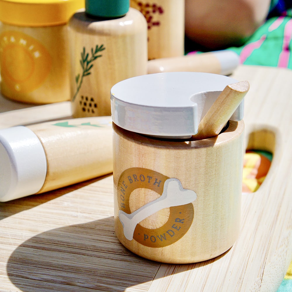 Wooden toy Natural Healers Kit with pestle and mortar, pretend Epsom salts, Manuka honey, bone broth, Tea Tree oil dropper, Boo Boo lotion, vitamins, arnica cream, herbal tea bags, and felt herbs for imaginative wellness play.