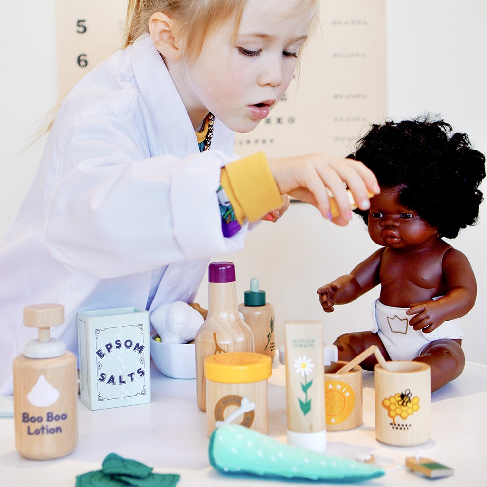Wooden toy Natural Healers Kit with pestle and mortar, pretend Epsom salts, Manuka honey, bone broth, Tea Tree oil dropper, Boo Boo lotion, vitamins, arnica cream, herbal tea bags, and felt herbs for imaginative wellness play.