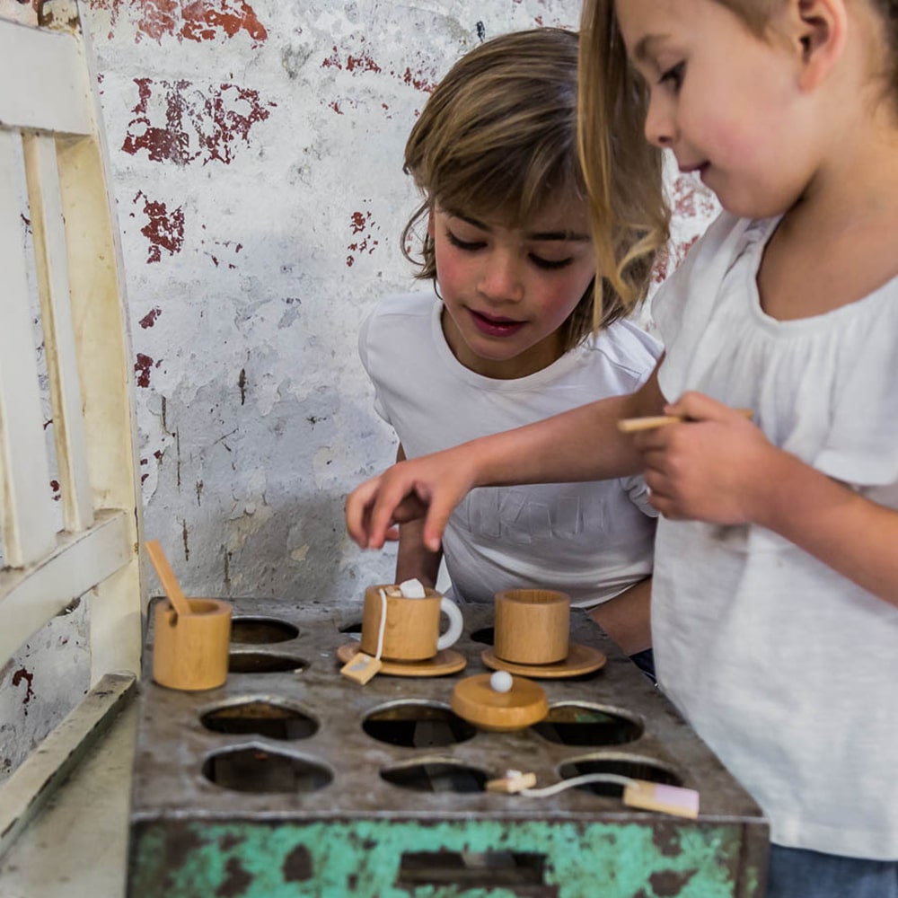 Wooden toy tea set for kids featuring teapot, cups, saucers, spoons, sugar bowl and milk jug, designed for pretend play, café role-play, and social learning activities.