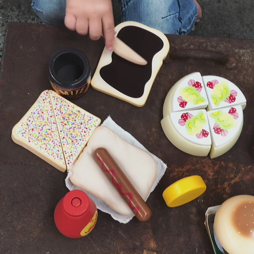 Make Me Iconic 38-piece wooden toy Aussie Food Set with Velcro lamington, pavlova slices, sausage in bread, meat pie, tomato sauce bottle, Vegemite toast, fairy bread, hot chips, Aussie burger with beetroot and egg, plus cardboard plates for extra pretend play.