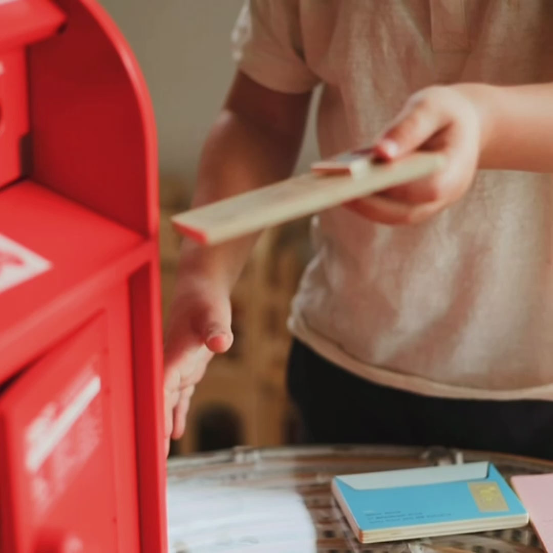 Make Me Iconic 13-piece wooden toy Post Box set with working slot, Velcro stamps, and envelopes—perfect for pretend mail play and developing fine motor skills.