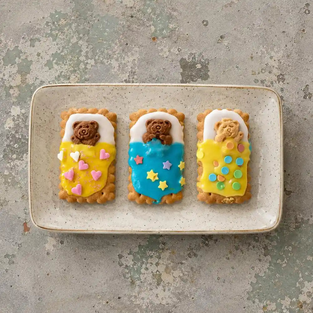 Colourful Arnott’s Tiny Teddy Bed Biscuits decorated with icing and sprinkles on a plate for a nostalgic Aussie kids baking activity.