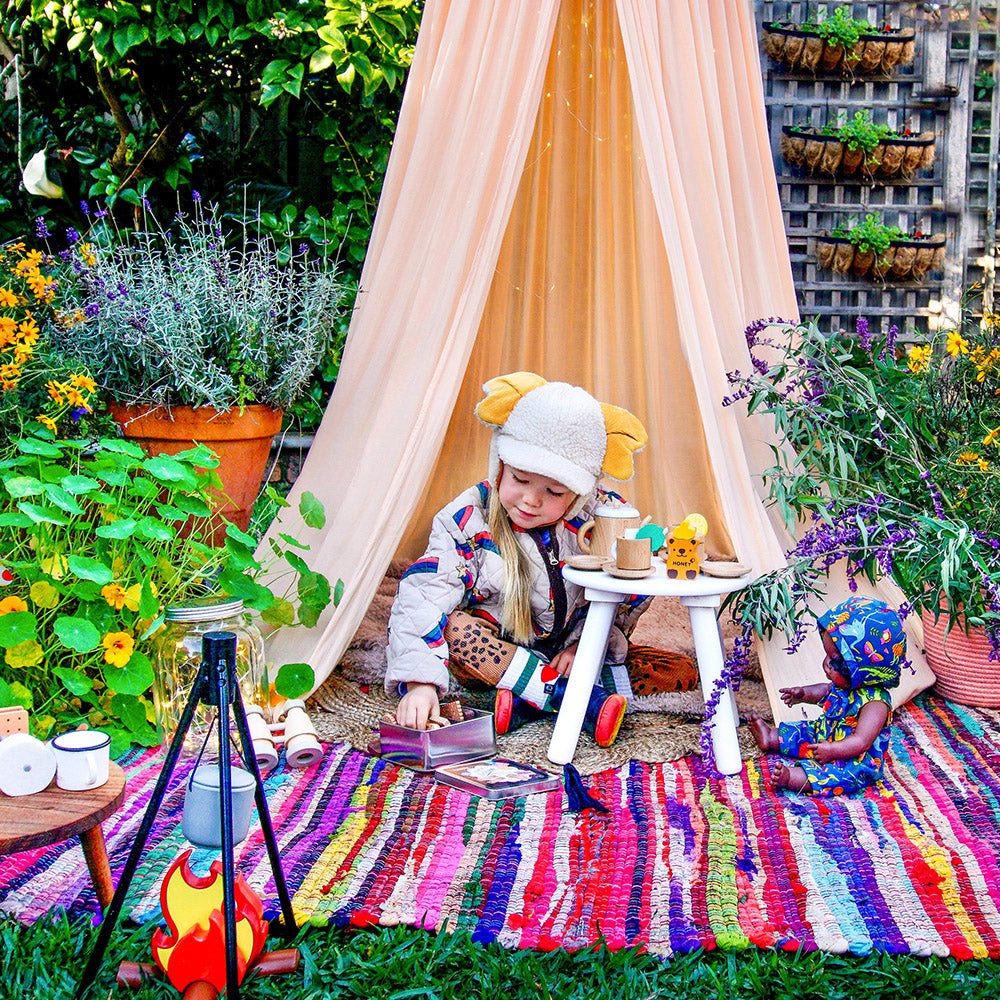 Child enjoying imaginative outdoor play in the backyard during winter using Make Me Iconic’s wooden campfire toy set, designed for screen-free fun and creative role play