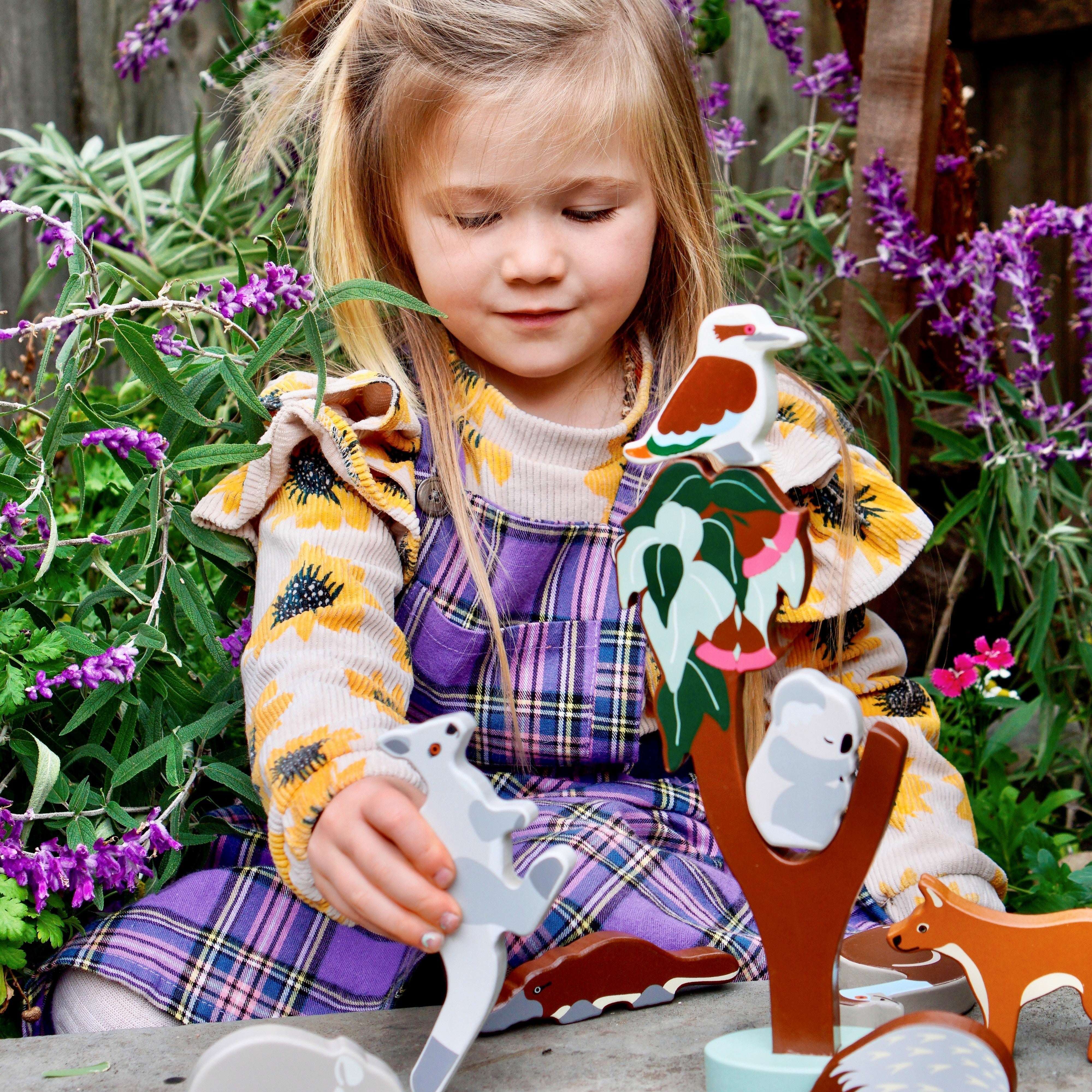 Children playing outdoors with wooden Aussie animal toys and natural healer kit promoting imaginative and nurturing play