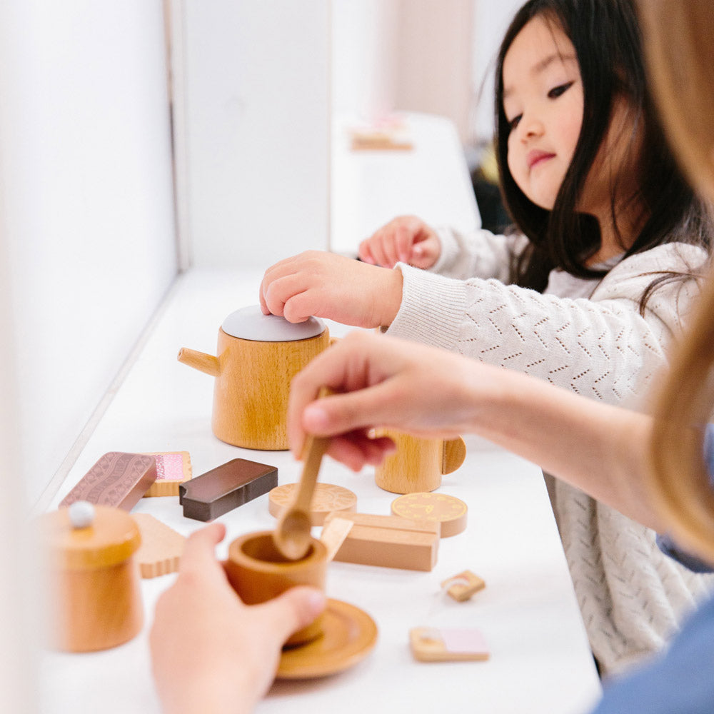 Kids playing with wooden food sets in a play kitchen, creating pretend meals. Best wooden food sets in Australia for creative kids and open ended play