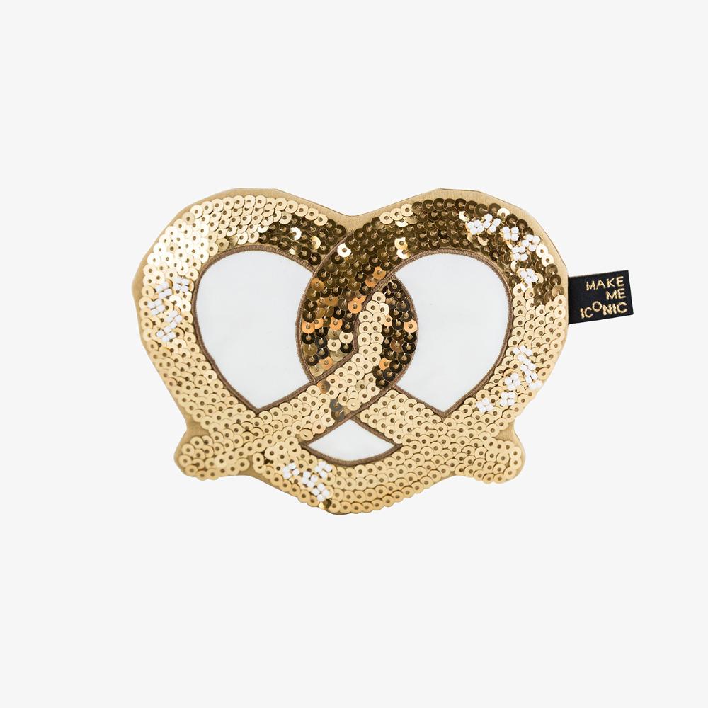 Make Me Iconic sequin pretzel purse with sparkling gold and pink sequins shaped like a pretzel, designed for holding small essentials like coins, keys, or hair clips. A fun, eye-catching accessory for kids, teens, and anyone who loves a playful touch of glamour.