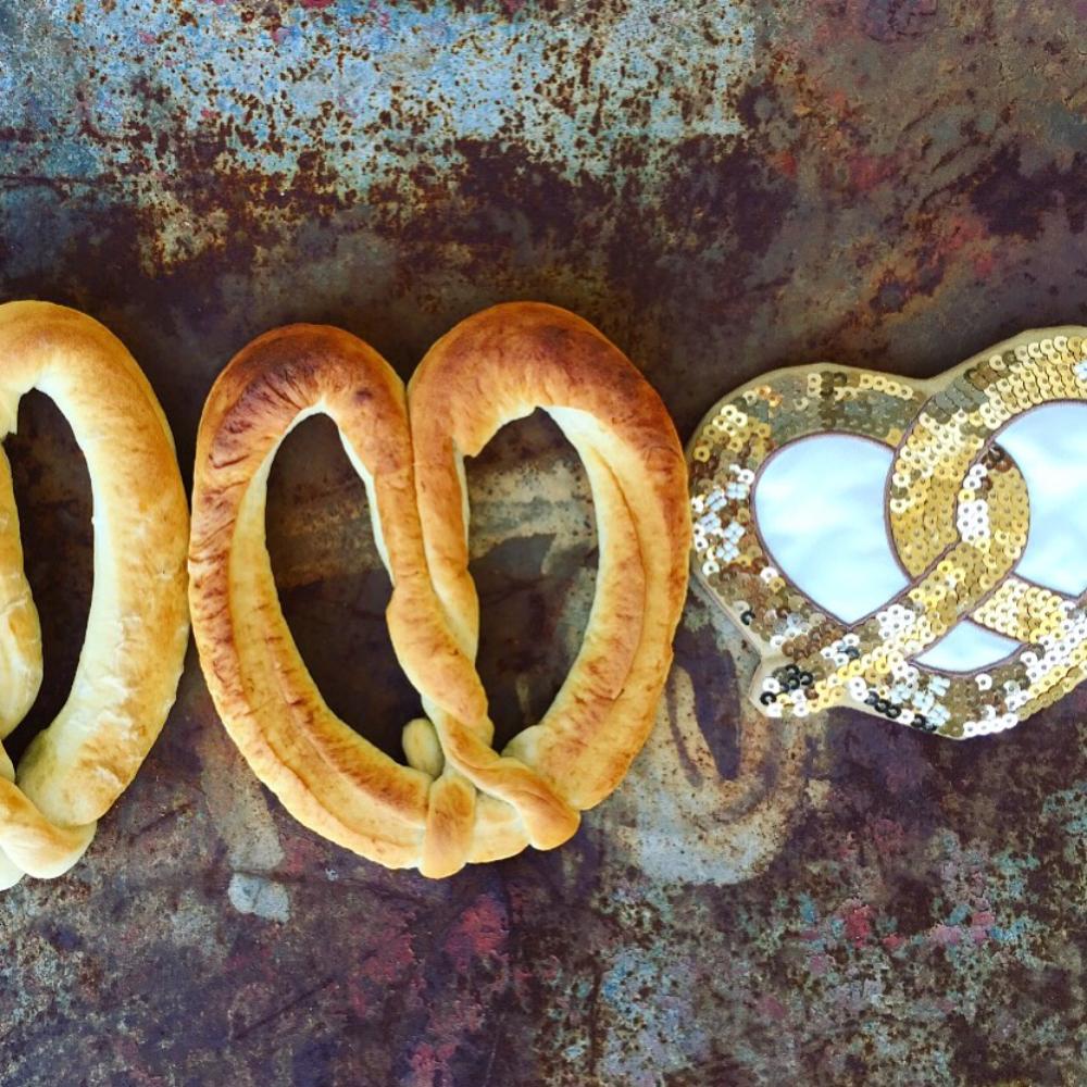 Make Me Iconic sequin pretzel purse with sparkling gold and pink sequins shaped like a pretzel, designed for holding small essentials like coins, keys, or hair clips. A fun, eye-catching accessory for kids, teens, and anyone who loves a playful touch of glamour.