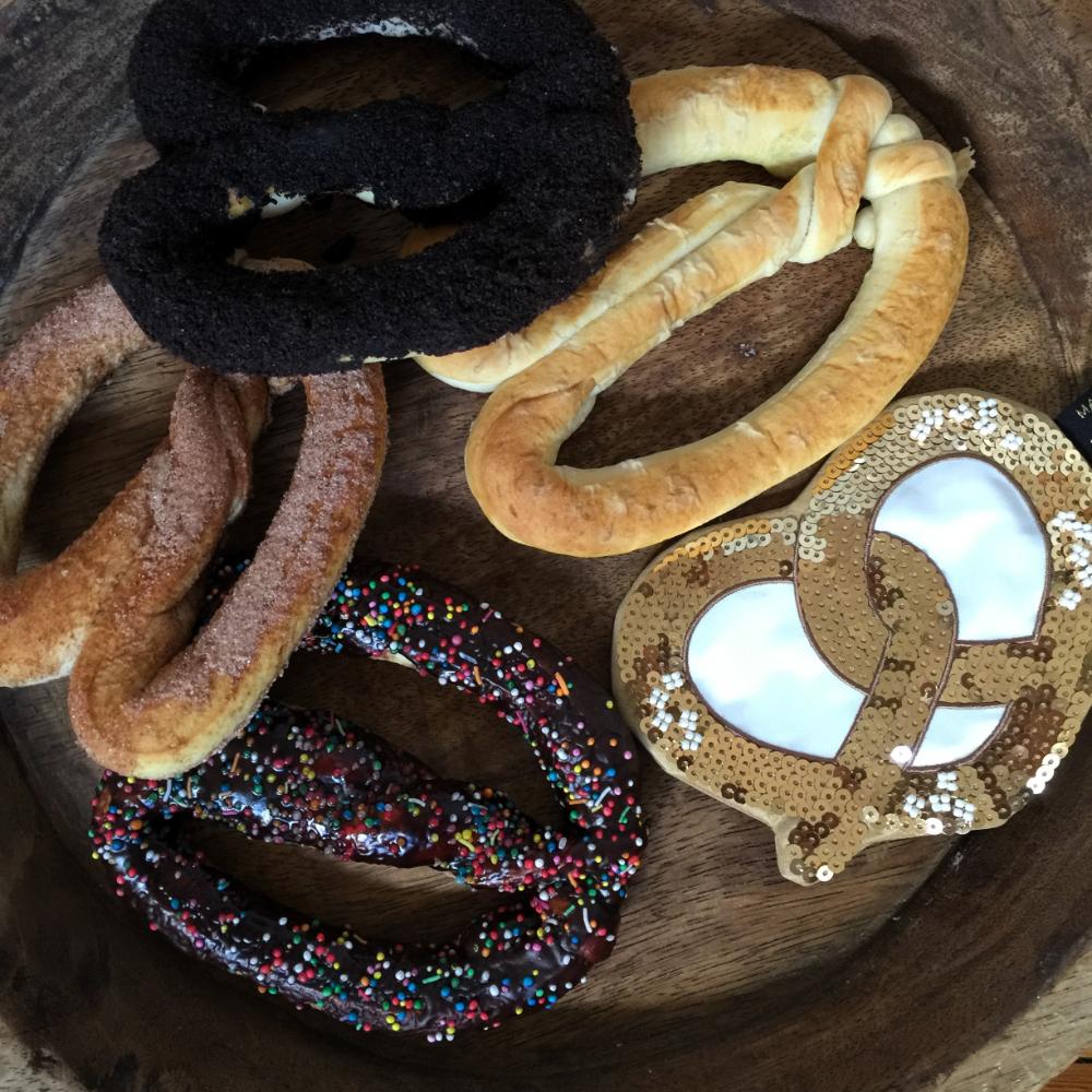 Make Me Iconic sequin pretzel purse with sparkling gold and pink sequins shaped like a pretzel, designed for holding small essentials like coins, keys, or hair clips. A fun, eye-catching accessory for kids, teens, and anyone who loves a playful touch of glamour.