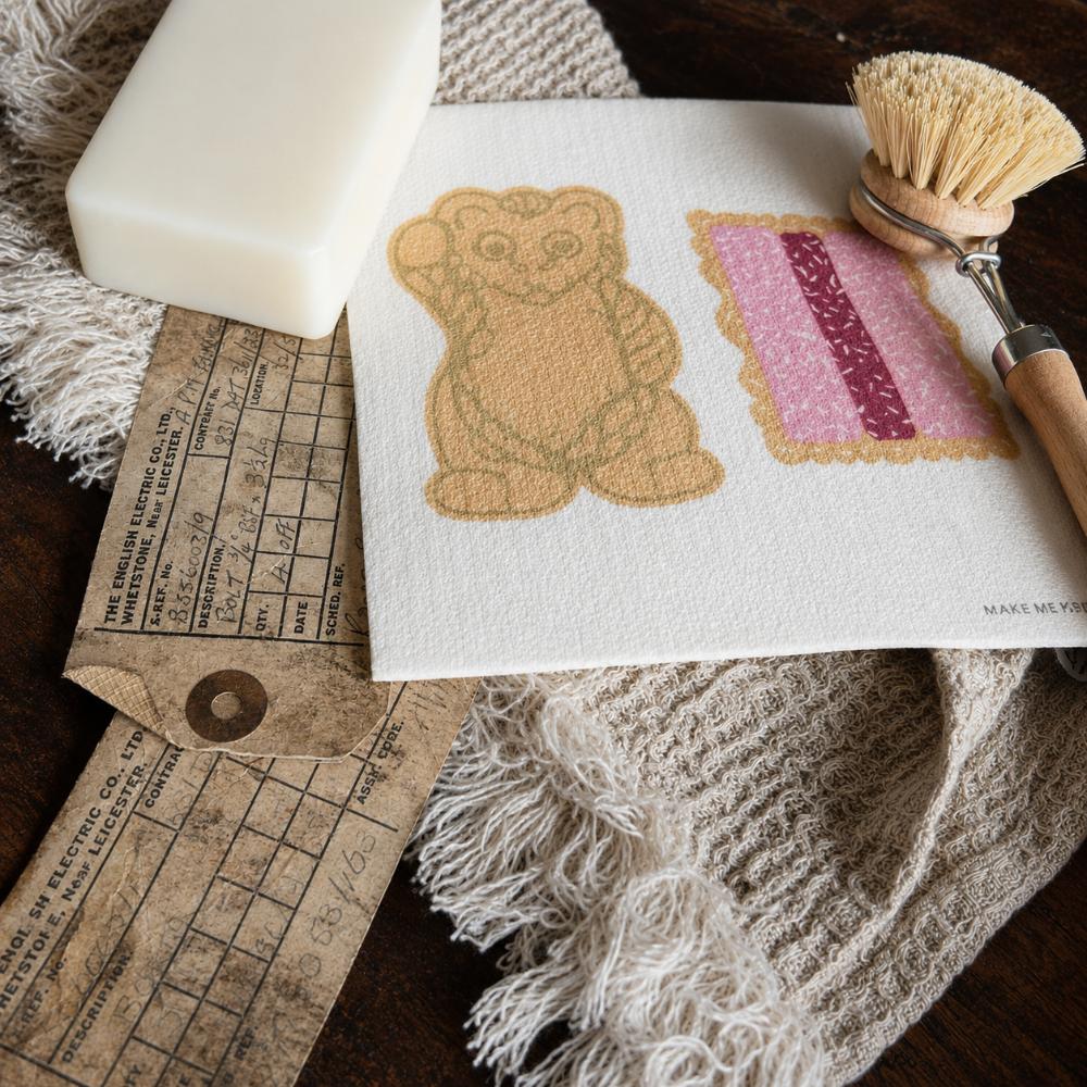 Iconic Bickies Swedish Dish Cloth featuring classic Australian biscuits including a Teddy Bear, Scotch Finger and Iced VoVo. Made from natural, eco-friendly fibres, this reusable dish cloth is super absorbent, durable and perfect for everyday kitchen cleaning. A nostalgic Aussie kitchen essential that pairs beautifully with Make Me Iconic tea towels and makes a thoughtful Australian gift or souvenir.