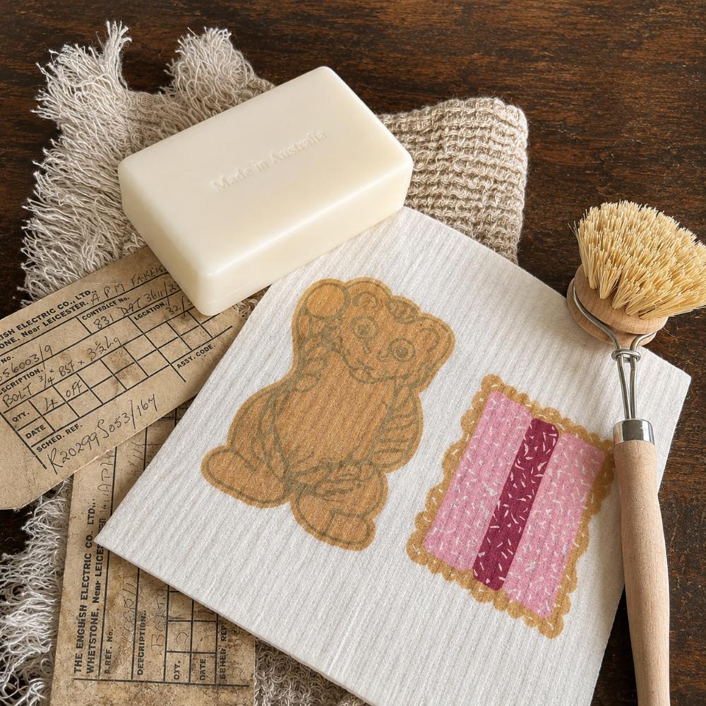 Iconic Bickies Swedish Dish Cloth featuring classic Australian biscuits including a Teddy Bear, Scotch Finger and Iced VoVo. Made from natural, eco-friendly fibres, this reusable dish cloth is super absorbent, durable and perfect for everyday kitchen cleaning. A nostalgic Aussie kitchen essential that pairs beautifully with Make Me Iconic tea towels and makes a thoughtful Australian gift or souvenir.