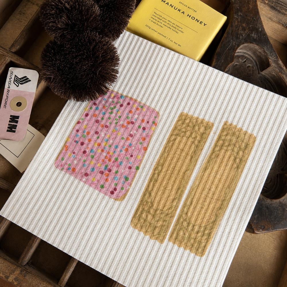 Iconic Bickies Swedish Dish Cloth featuring classic Australian biscuits including a Teddy Bear, Scotch Finger and Iced VoVo. Made from natural, eco-friendly fibres, this reusable dish cloth is super absorbent, durable and perfect for everyday kitchen cleaning. A nostalgic Aussie kitchen essential that pairs beautifully with Make Me Iconic tea towels and makes a thoughtful Australian gift or souvenir.
