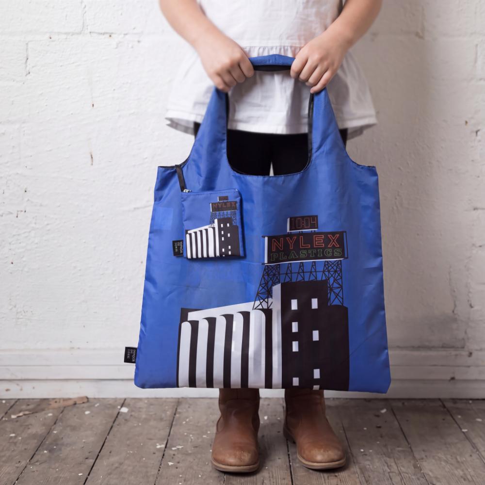 A Make Me Iconic foldable reusable shopping bag featuring Melbourne's iconic Nylex sign design. Made from 100% recycled fabric, this lightweight eco-friendly tote folds into a compact pouch and is perfect for shopping, travel, or everyday use.