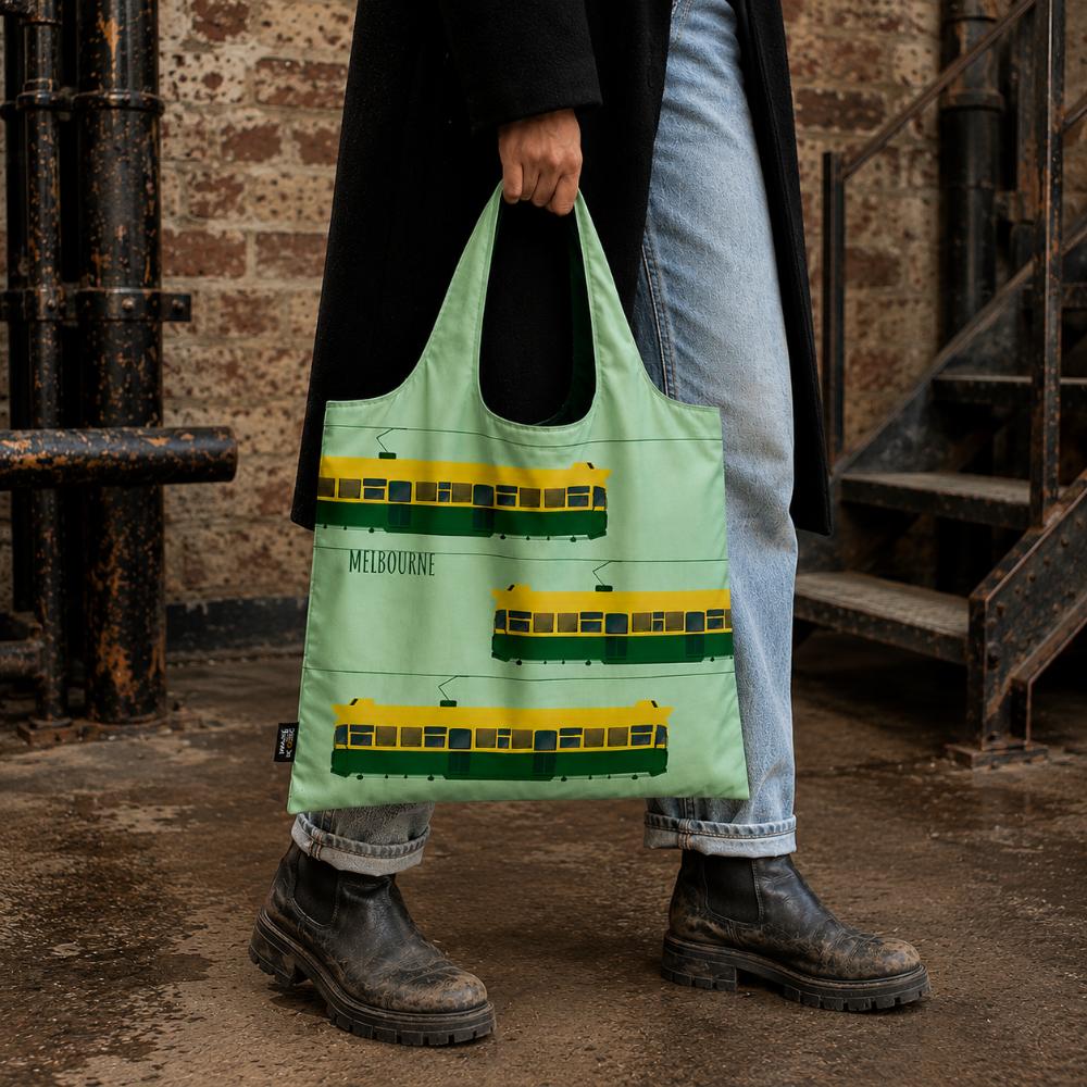 A Make Me Iconic reusable foldable shopping bag featuring Melbourne's iconic green and yellow W-Class tram. Made from 100% recycled fabric, this lightweight eco-friendly tote folds into a compact pouch and holds up to 20kg for everyday shopping.