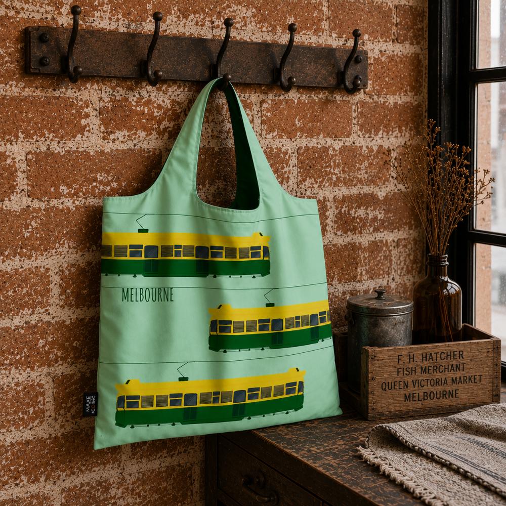 A Make Me Iconic reusable foldable shopping bag featuring Melbourne's iconic green and yellow W-Class tram. Made from 100% recycled fabric, this lightweight eco-friendly tote folds into a compact pouch and holds up to 20kg for everyday shopping.