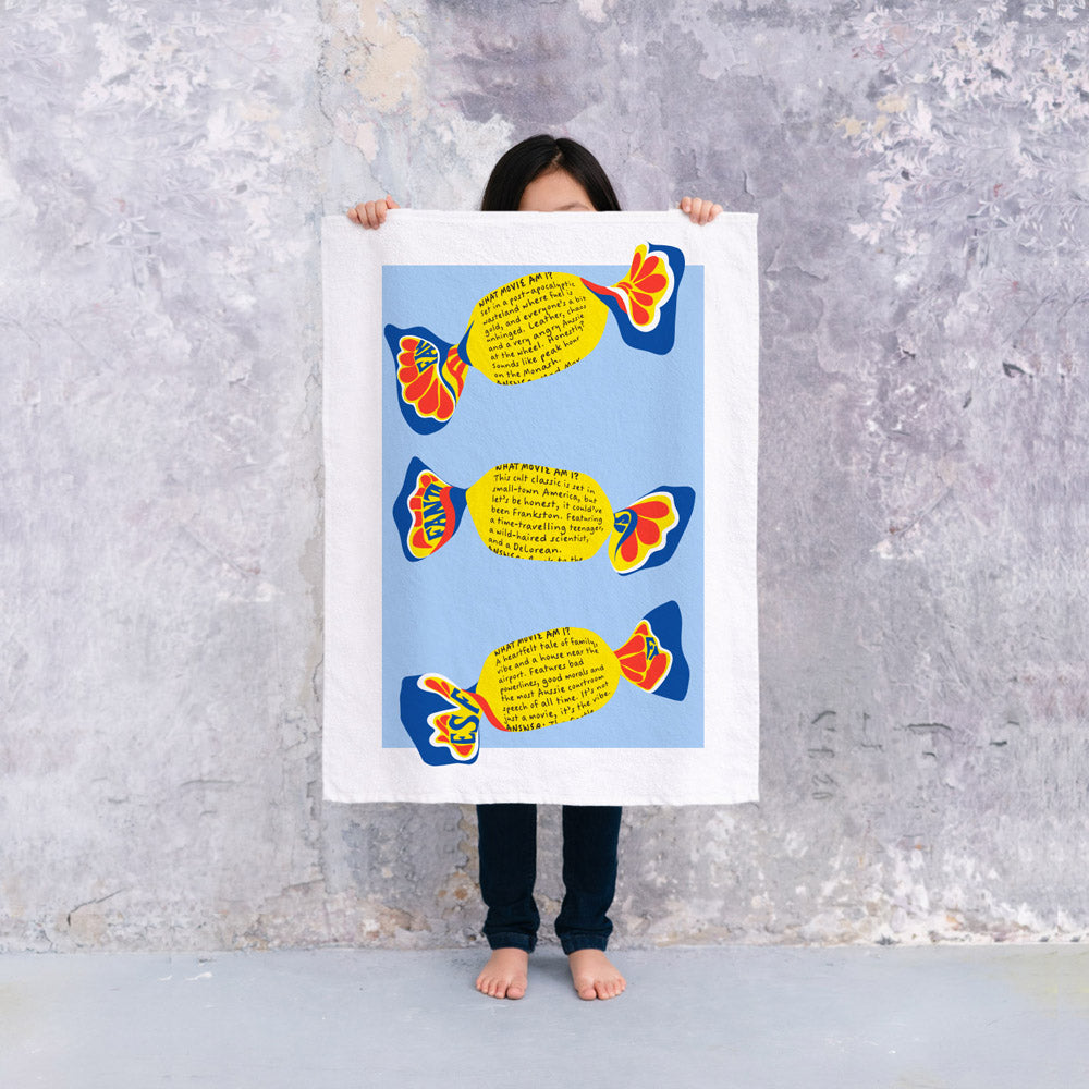 Fantales Tea Towel featuring Australia's iconic chocolate caramel lolly wrappers and classic “What Movie Am I?” trivia. A nostalgic Australian gift and souvenir.