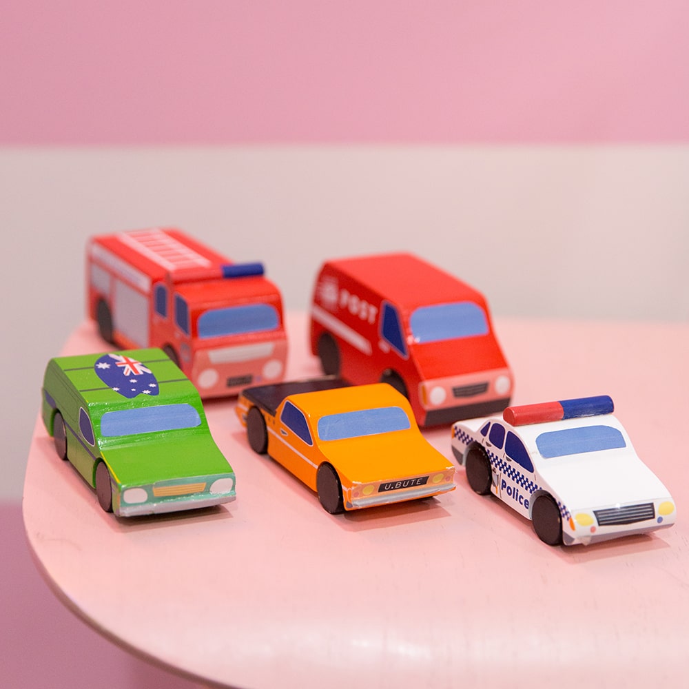 Aussie wooden toy vehicle set featuring Sandman Panel Van, retro-orange ute, fire truck, and postie bike for imaginative play
