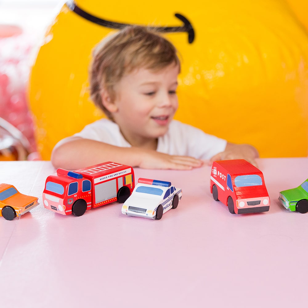 Aussie wooden toy vehicle set featuring Sandman Panel Van, retro-orange ute, fire truck, and postie bike for imaginative play