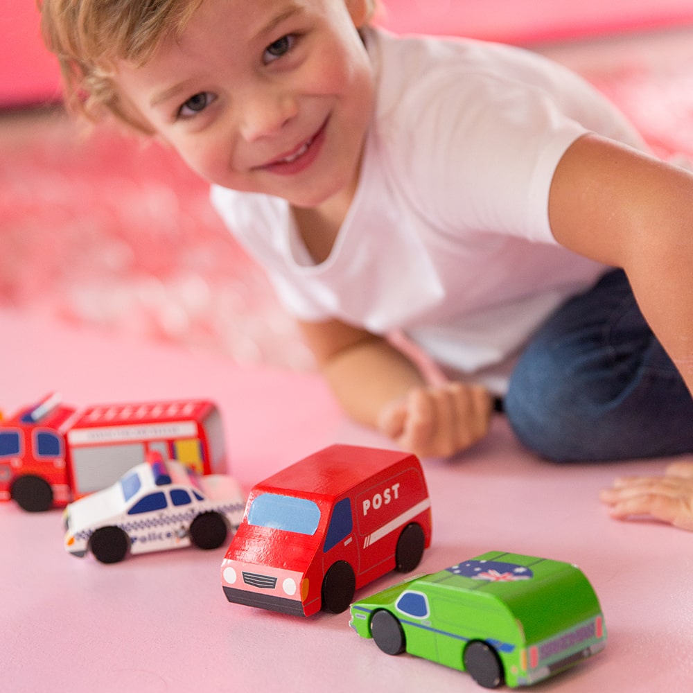 Aussie wooden toy vehicle set featuring Sandman Panel Van, retro-orange ute, fire truck, and postie bike for imaginative play