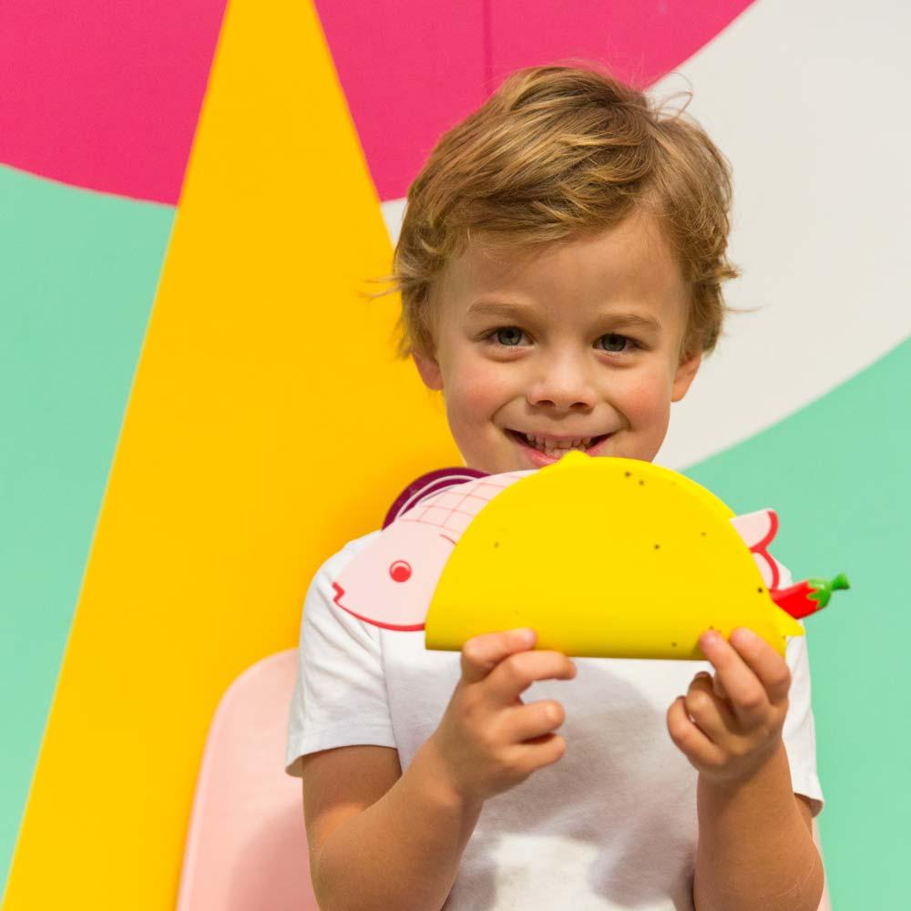 Make Me Iconic 21-piece wooden toy play Taco Kit featuring stand-up taco shells, prawns on skewers, paper takeaway bags, felt toppings, and pretend condiments like chilli sauce and sour cream for imaginative role play.