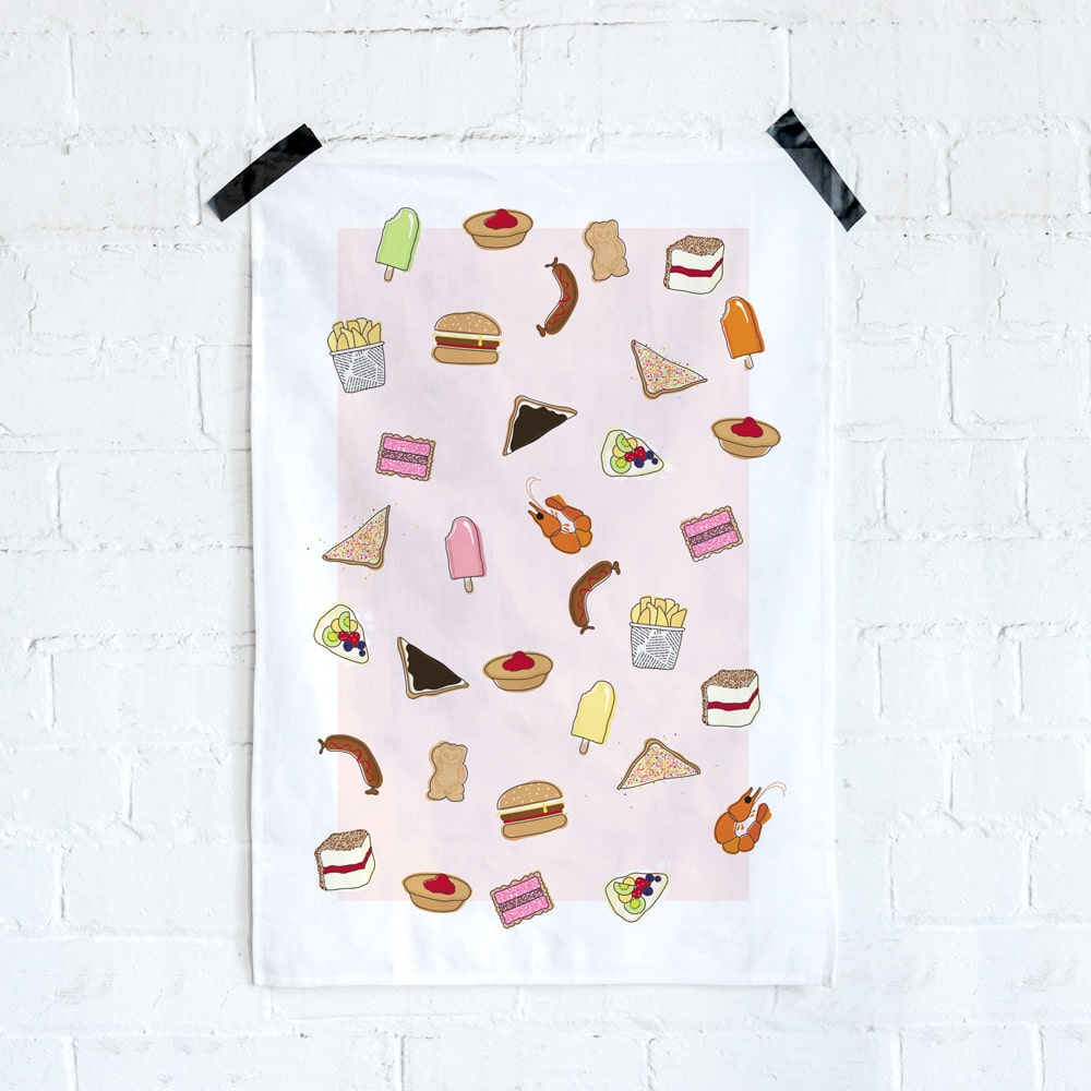 Make Me Iconic tea towel featuring iconic Australian foods, such as Vegemite toast, fairy bread, meat pies, pavlova, and lamingtons. A colourful, quirky kitchen accessory celebrating Aussie culture and nostalgia