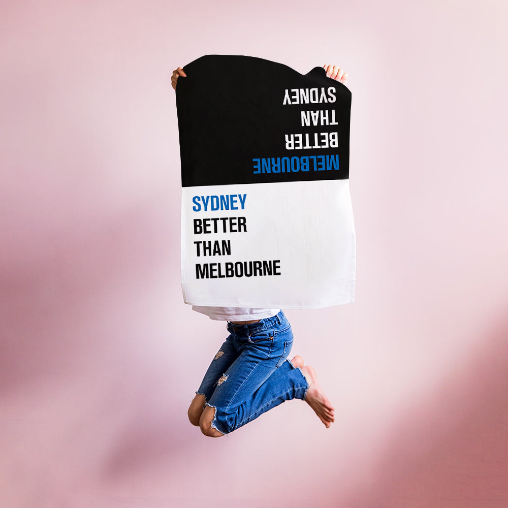 Make Me Iconic Choice Tea Towel with bold double-sided print, Melbourne vs Sydney rivalry in playful, nostalgic kitchen style.
