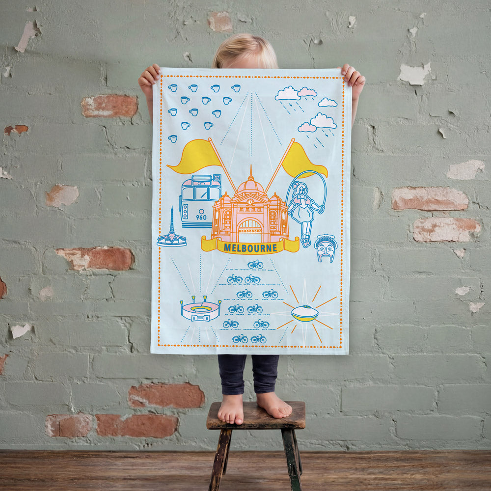 Iconic Melbourne Coat of Arms Tea Towel featuring Melbourne-inspired illustrations including a tram, coffee cup, football, city landmarks and weather symbols, celebrating the culture, history and character of Melbourne.