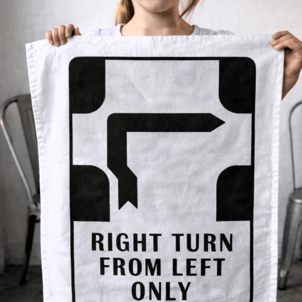 Make Me Iconic’ Melbourne Hook Turn Tea Towel featuring the iconic "Right Turn from Left Only" road sign in bold black and white. A playful nod to Melbourne’s famously confusing driving rule, printed on a cotton-linen blend towel perfect for kitchens, gifts, or nostalgic decor.