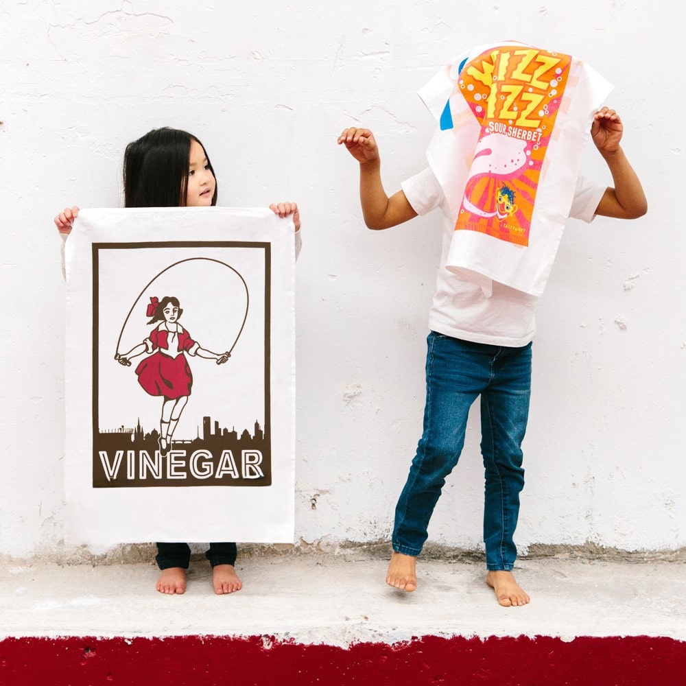 Make Me Iconic Skipping Girl tea towel featuring Melbourne’s iconic Little Audrey neon sign, a nostalgic tribute to the city’s skyline.