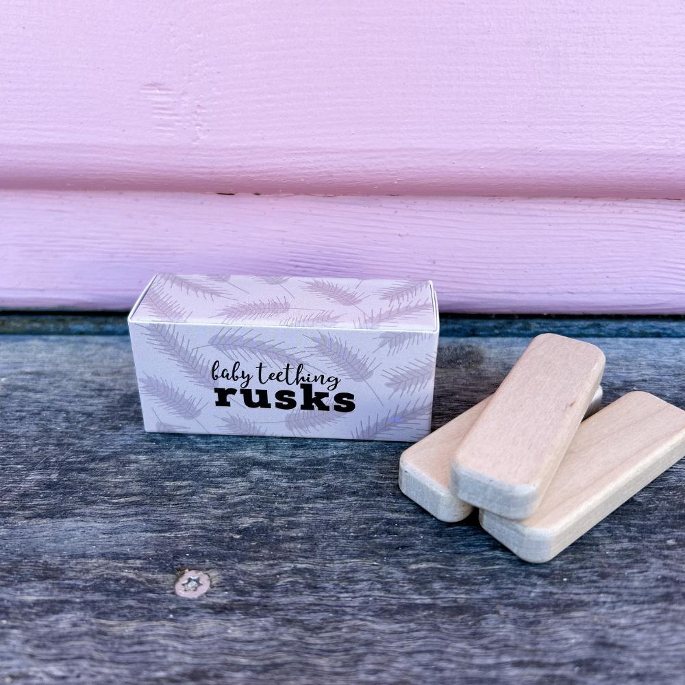 Make Me Iconic set of 3 wooden toy doll rusks in a cardboard box, designed for pretend feeding and nurturing role-play. Perfect for developing empathy, fine motor skills, and imaginative play in young children.