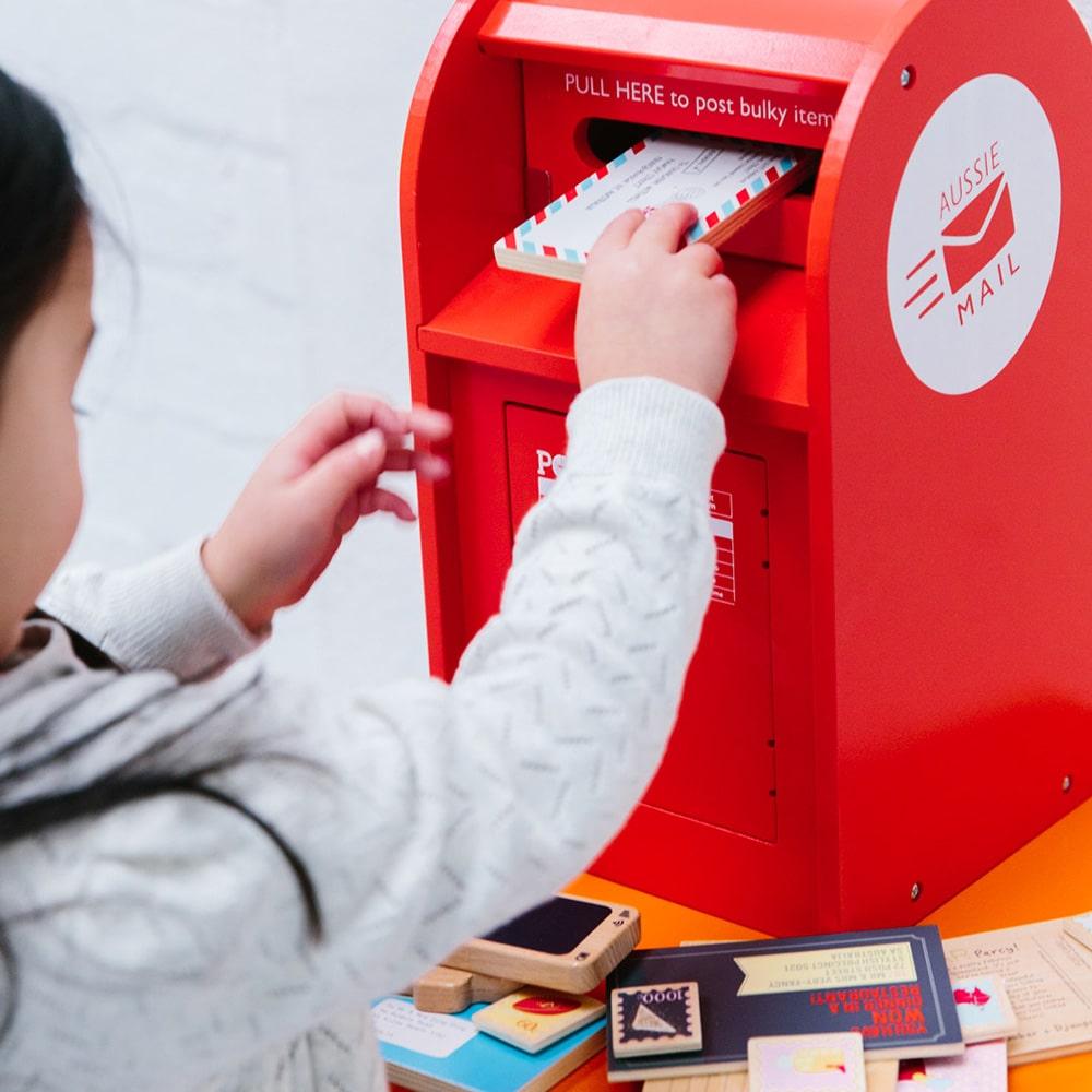 Australian Post Box wooden toy featuring a working mail slot, wooden letters, postcards and stamps. A nostalgic role-play toy inspired by the iconic red Australia Post Box.