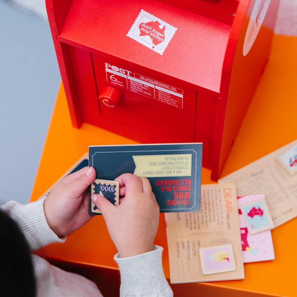 Australian Post Box wooden toy featuring a working mail slot, wooden letters, postcards and stamps. A nostalgic role-play toy inspired by the iconic red Australia Post Box.